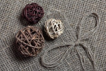 Coarse linen fabric. On it are rattan balls and a bow of linen threads.