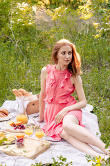 The red haired woman in pink dress with glass of orange juice.