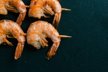 Picks with fried prawns on black slate surface