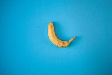 Single yellow banana on a blue background