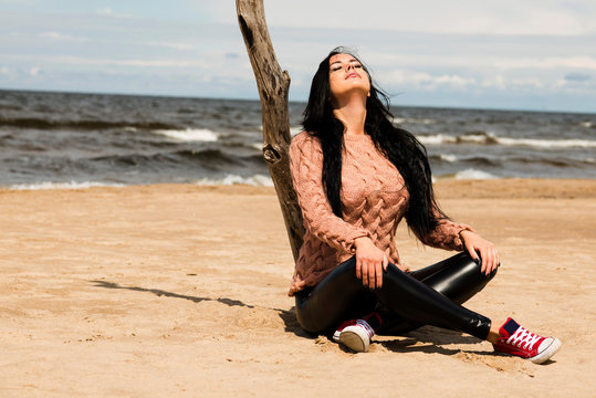 The beautiful brunette poses in a knitted pullover on the coast of the Baltic Sea