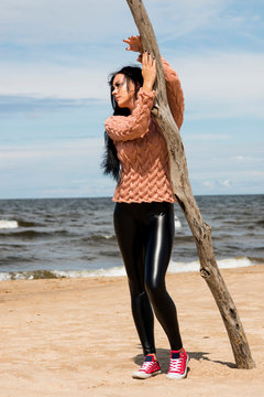 The beautiful brunette poses in a knitted pullover on the coast of the Baltic Sea