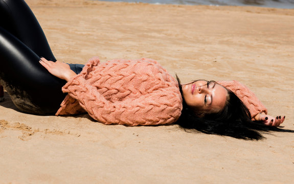 The beautiful brunette poses in a knitted pullover on the coast of the Baltic Sea