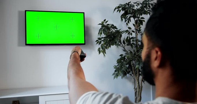 African-american male turning on greenscreen tv with remote control, advertisement template, backview