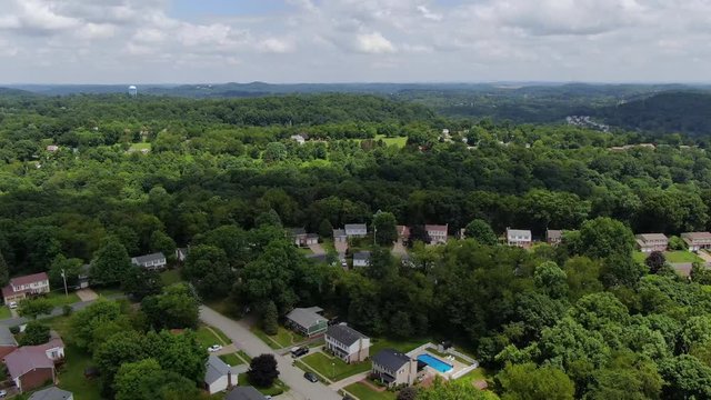 A forward moving aerial wide shot view flying above a typical middle class Pennsylvania residential neighborhood. Pittsburgh suburbs.  	