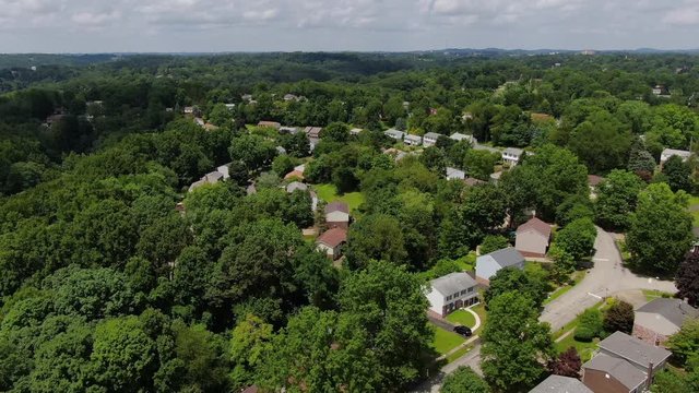A reverse moving aerial view flying above a typical middle class Pennsylvania residential neighborhood. Pittsburgh suburbs.  	