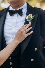 woman fixes accessories groom Scottish tuxedo