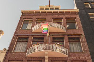A rainbow flag (LGBT movement) seen from the ground up flutters in the wind from right to left...