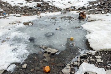 Garbage scattered over snowy mountain. Let's save the planet and recycle the excess garbage. Pollution Concept