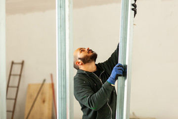 Worker builds a plasterboard wall.