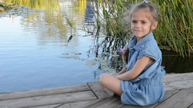 Toddler girl watching colorful Koi or carps fish in the pond, petting zoo