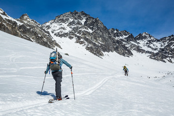 Fototapeta na wymiar Two skiers skinning up slope near Snowbird Mine in Hatcher Pass area in the Talkeetna Mountains, Alaska.