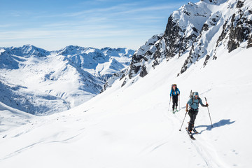 Fototapeta na wymiar Skiers moving uphill on hot sunny day in the Alaska backcountry.