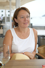 Portrait of a happy woman sitting next to the sea and daydreaming