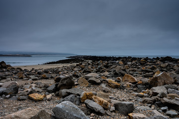 Rocky coast jutting out to the ocean with a dark sky.