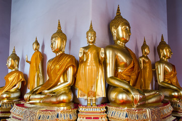 Golden sitting and standing buddha statues at a temple.