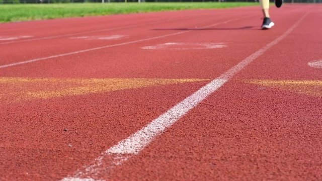 Close-up feet of woman running on track at outdoor