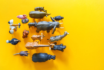 African animals in plastic. The figure of a mammal is tangled in the package. Yellow background.