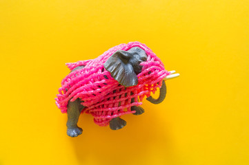 African animal elephant in plastic. Suffering from garbage. Yellow background.
