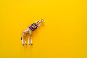 African animal giraffe in plastic. Suffering from garbage. Yellow background.