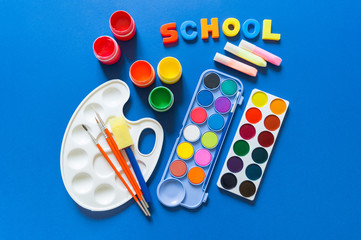 Stationery flat lay. Material for drawing and the artist lies on a blue background.