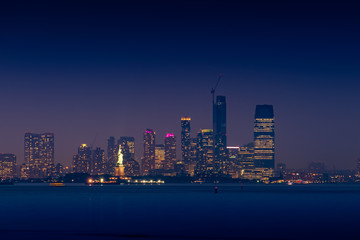 Obraz premium Statue of Liberty illuminated with lights at dusk after sunset in New York City, view from New York Bay