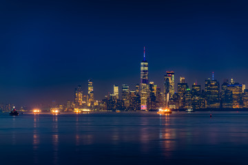 Obraz na płótnie Canvas New York City Manhattan skyline illuminated with lights at dusk after sunset, view from New York Bay and Staten Island