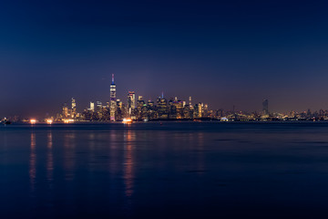 New York City Manhattan skyline illuminated with lights at dusk after sunset, view from New York Bay and Staten Island, water view