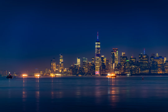 New York City Manhattan skyline illuminated with lights at dusk after sunset, view from New York Bay and Staten Island © Happy Stock