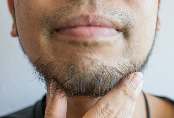 Cropped shot of Asian man touching his beard grows on a part of lower face. Beard is the collection...