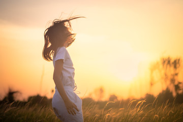 Beauty Girl Outdoors enjoying nature. Beautiful Teenage Model girl in the Spring Field, Sun Light.