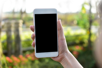 Hand holding Mobile Smart phone on Green Background