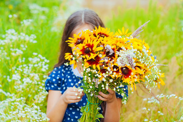 Little adorable girl gathered a bouquet of wild flowers