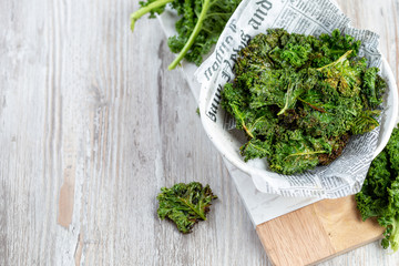 Homemade Green Kale Chips on vintage newspapper, white background