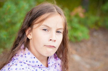 Fototapeta premium Sad little girl is looking with serious face at camera