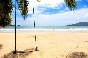 Summer concept. Wood swing hanging from coconut palm tree over beach sea. Asia Thailand. with copy space for text or design