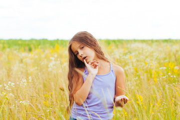 Portrait of a little adorable little girl smiling, in field with yellow flowers