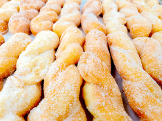 Closeup and crop lots of twist doughnut with sugar on shelf in the bakery shop background and wallpaper. Doughnut is the one causes disease of coronary artery disease and obesity.