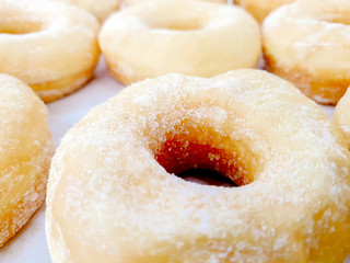Closeup and crop lots of doughnut with sugar on shelf in the bakery shop background and wallpaper. Doughnut is the one causes disease of coronary artery disease and obesity.