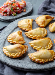 Different little cocktail EMPANADAS on stone plate with tomato sauce and guacamole . Gray background. Latin American and Spanish tipical food