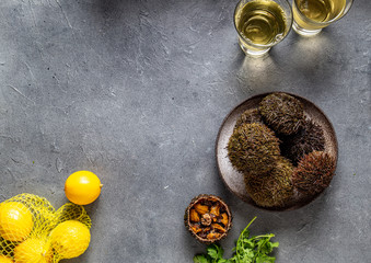 Pacific Sea urchins on gray background with lemon. cilantro and white wine. top view