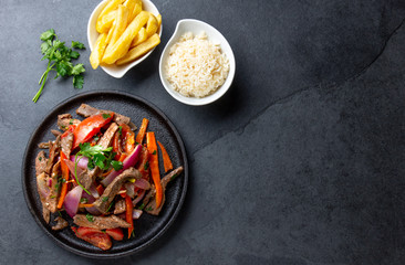 Peruvian dish Lomo saltado - beef tenderloin with purple onion, yellow chili, tomatoes served...