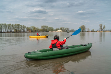 Kayak fishing at lake. Two fisherwomen on inflatable boats with fishing tackle.