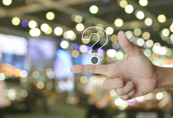 Question mark sign icon on finger over blur light and shadow of shopping mall, Business customer service and support concept
