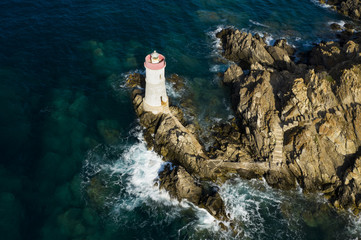 View from above, stunning aerial view of an old and beautiful lighthouse located on a rocky coast...