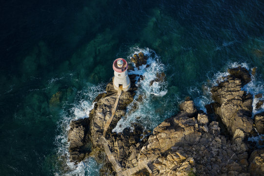 View From Above, Stunning Aerial View Of An Old And Beautiful Lighthouse Located On A Rocky Coast Bathed By A Rough Sea. Faro Di Capo Ferro, Porto Cervo, Sardinia, Italy.