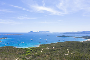 View from above, stunning aerial view of a beautiful green coast bathed by a turquoise sea with some boats and yachts. (Emerald Coast) Sardinia, Italy.