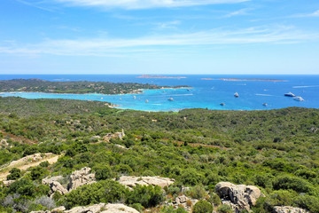View from above, stunning aerial view of a beautiful green coast bathed by a turquoise sea with some boats and yachts. Costa Smeralda (Emerald Coast) Sardinia, Italy.