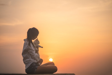 Silhouette of free woman enjoying freedom feeling happy with her cat at sunset