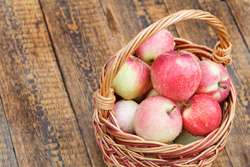 Red apples in wicker basket on wooden boards